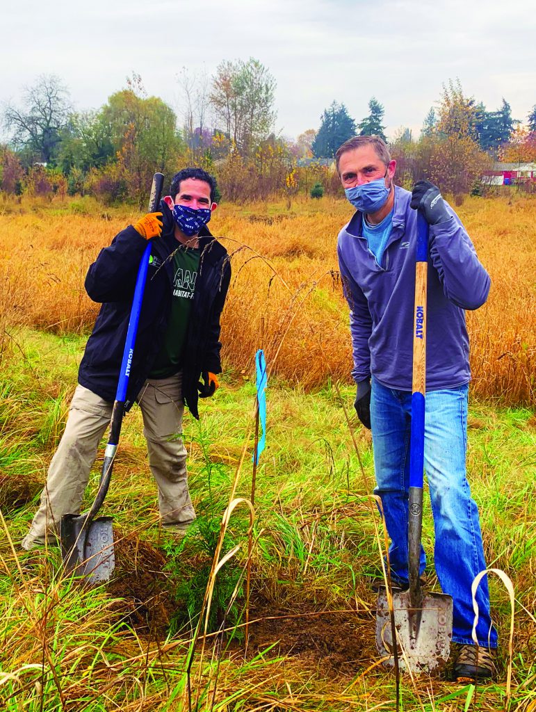 Two volunteers help plant a conifer sapling at the City of Puyallup's Peck Property