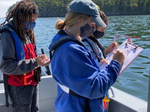 Salish Sea School students and faculty take notes and record data on the deck of a boat out on the water in Puget Sound