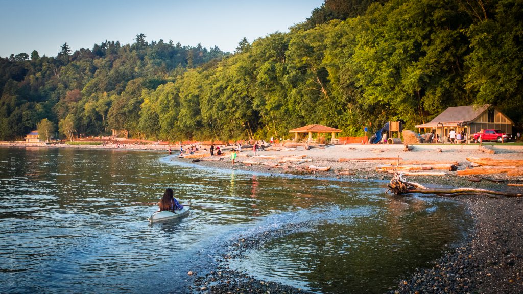 Post-restoration photo of Seahurst Park in Burien, showing a kayaker paddling in the water and people enjoying the beach.