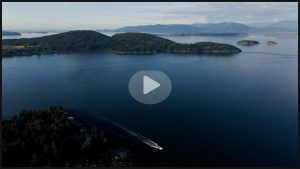 Screenshot from the Puget Sound Geographic Program funds at work video, showing an aerial shot of a boat travelling through Puget Sound.