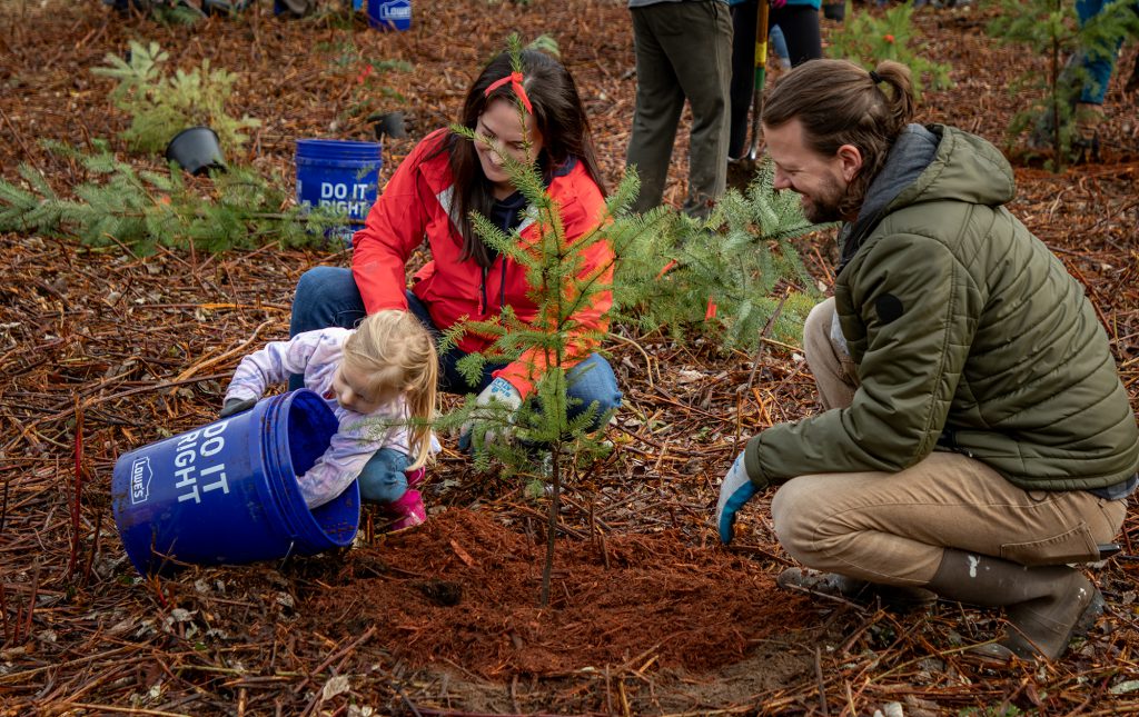 A family working together to plan an evergreen sapling at Lake Sammamish State Park.